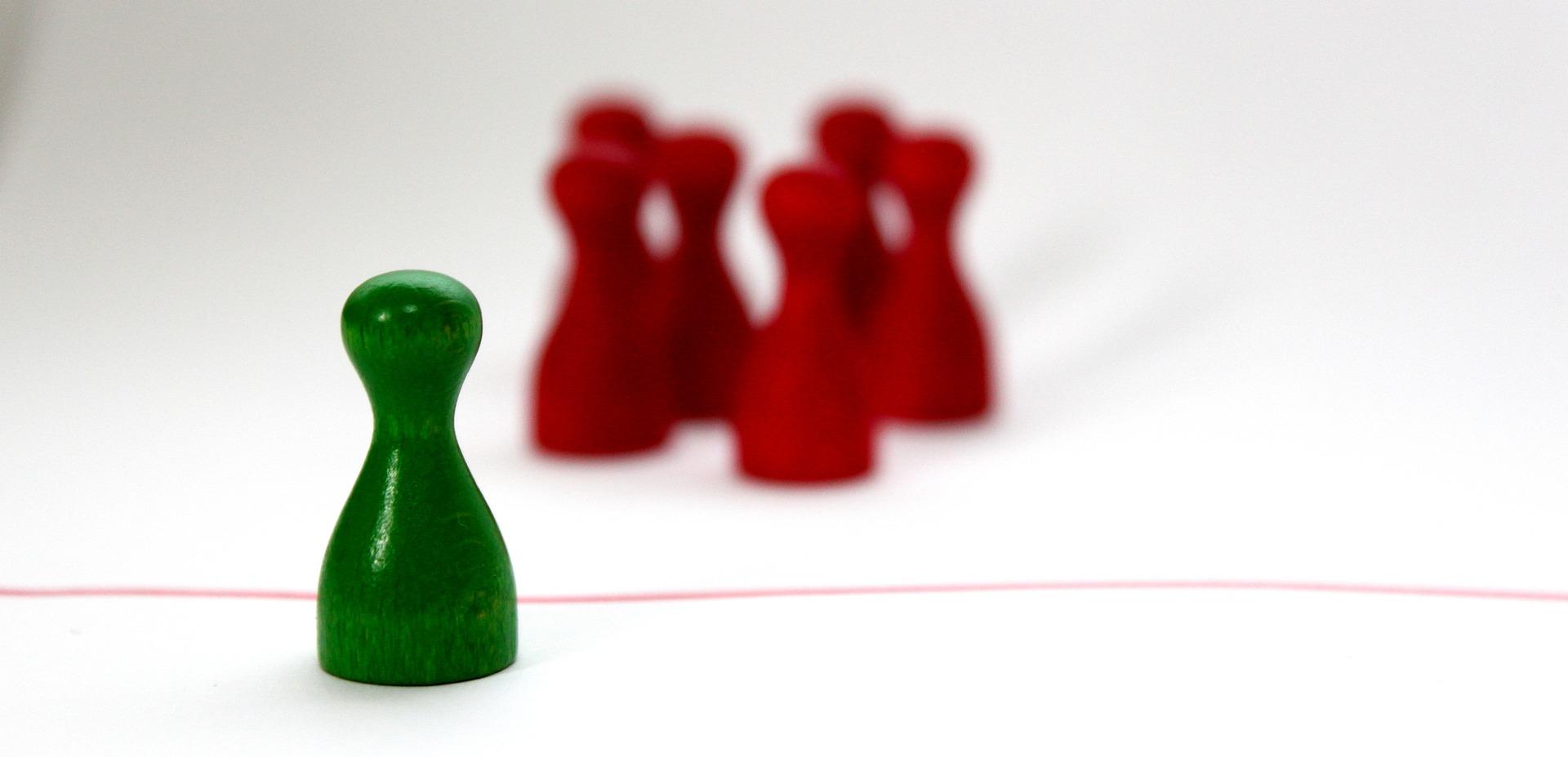 Piezas de ajedrez rojas hacen bullyng a pieza verde