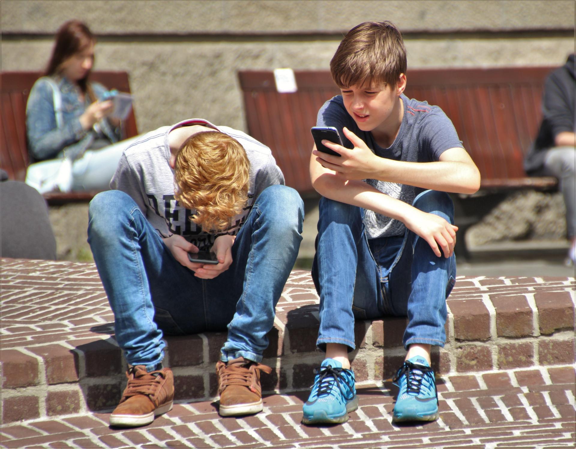 Nios con móviles sentados en la calle
